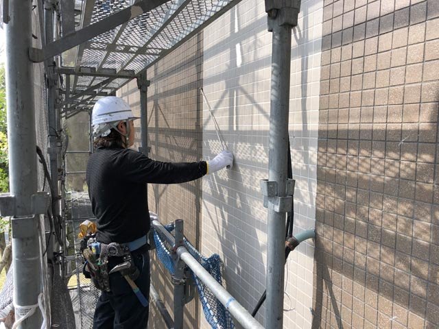 足場の上で外壁タイルを補修する職人